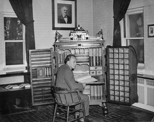 Professor Russell L. Carpenter sitting at P.T. Barnum's desk, ca. 1955