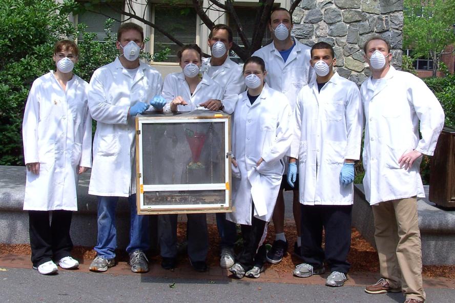 Biology faculty and students in masks with butterfly cage