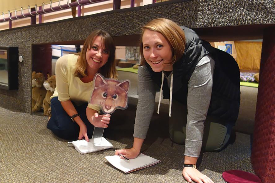 Two students holding a fox image in a classroom setting