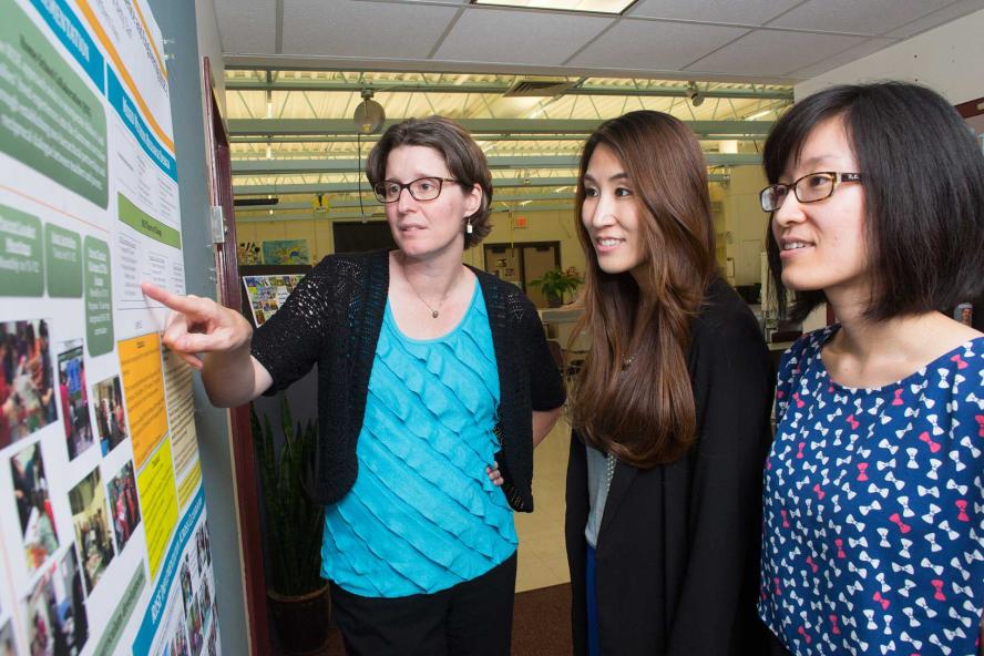 Professor working with students and pointing to a display