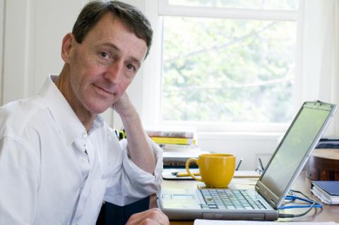 a man in a white shirt sitting in front of an open laptop 