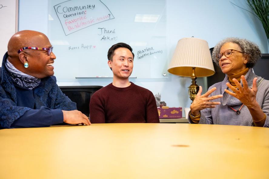 Three people sitting at a table, talking