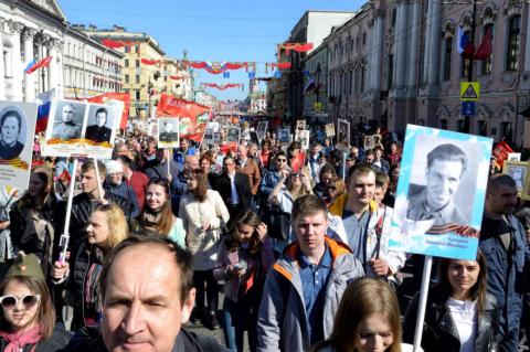 A crowd of people carrying posters of black and white photos of war veterans in St. Petersburg, Russia