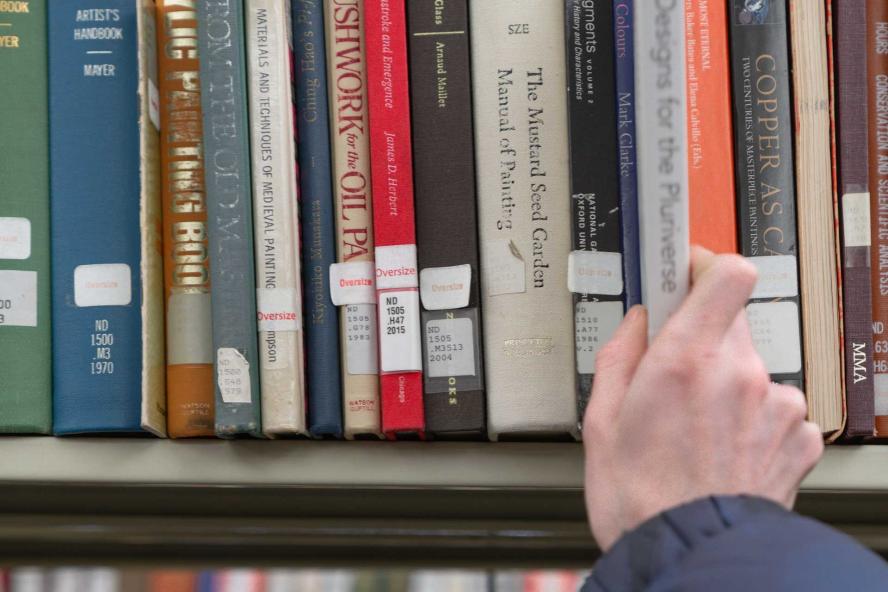 View of a person's hand removing a book from a shelf in Tisch Library