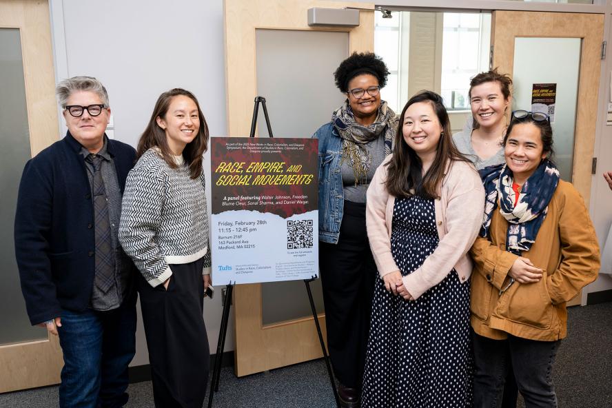 Six RCD Faculty/Affiliates posing in front of an event poster