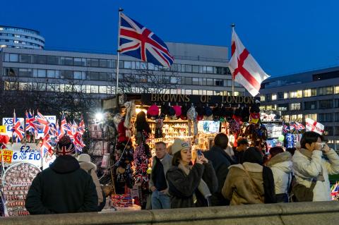 A group of people gathered around a stall adorned with British flags