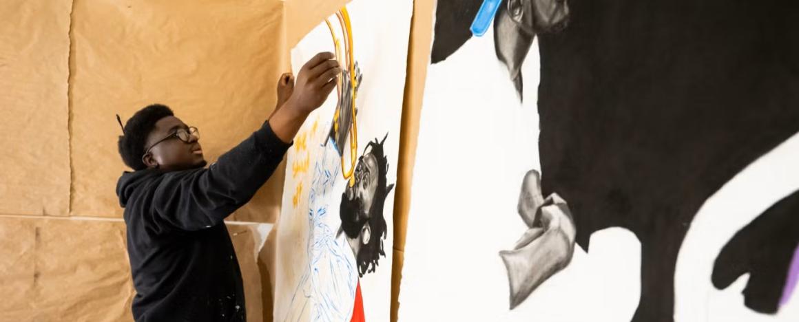 Student putting up artwork on a wall