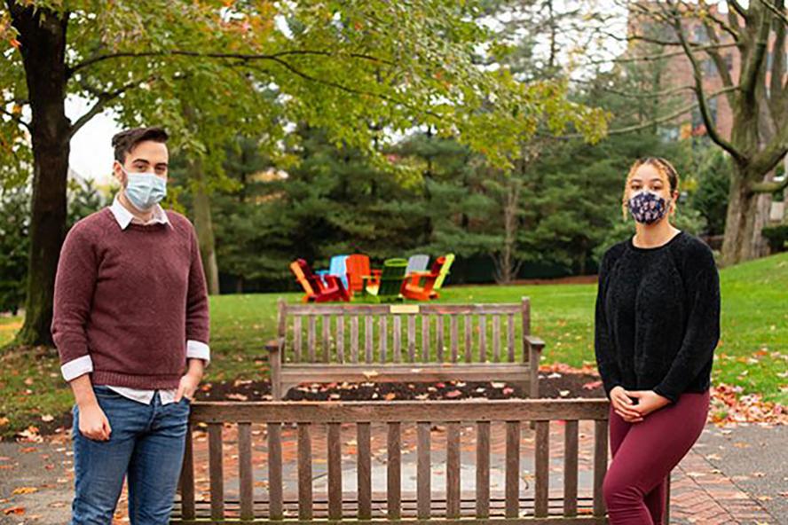 Two students with masks standing 10 feet apart on Tufts quad