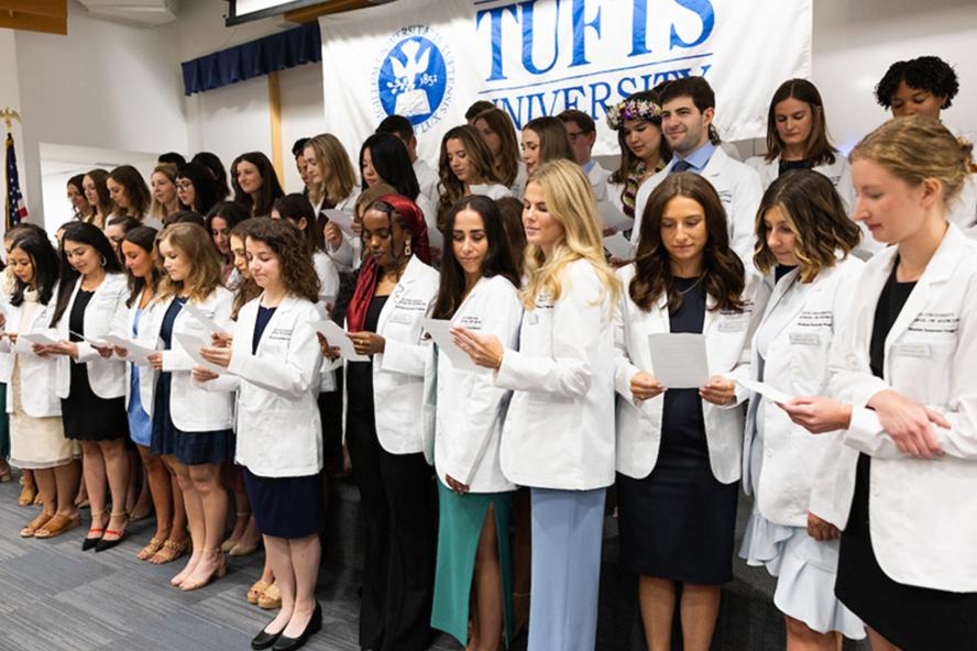 Students standing together in white coats at the Tufts Medical School