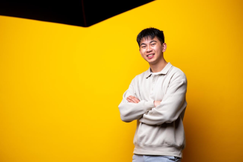 Dan Nguyen stands in front of a yellow backdrop. He uses his advocacy and research to improve global access to safe water, sanitation, and hygiene.