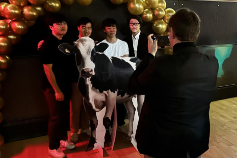 Students standing behind a large cutout of a cow
