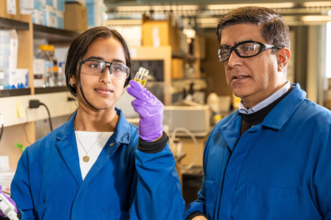 Two researchers in blue lab coats in a laboratory setting