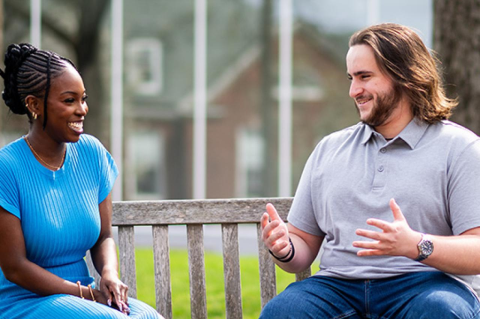 a woman in a blue dress sits beside a man in a gray shirt on a bench