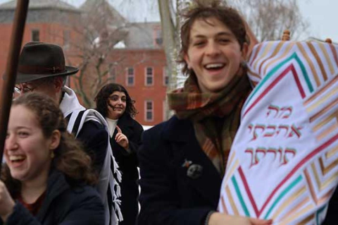 a student holds one of the Torah scrolls as part of the procession of Tufts community members