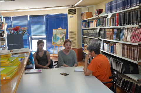 Three women engaged in a discussion at a library