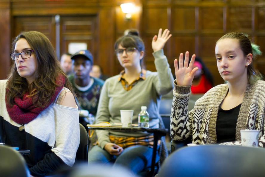 Women in classroom raising hands